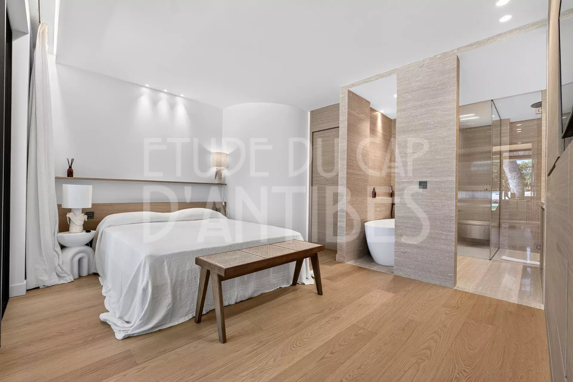 Chambre d'une villa moderne avec salle de bain attenante, décoration épurée et lumière naturelle.