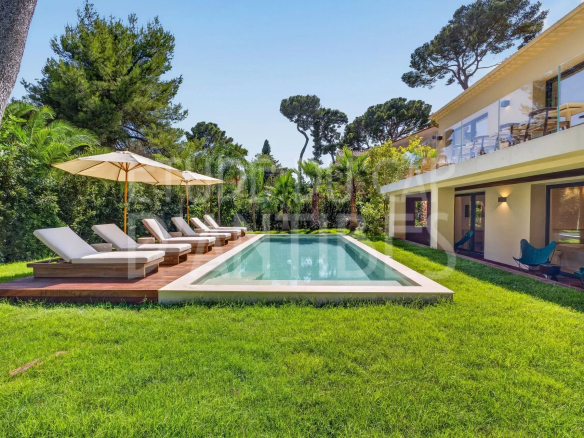Villa moderne avec piscine et chaises longues dans un jardin arboré à Antibes.