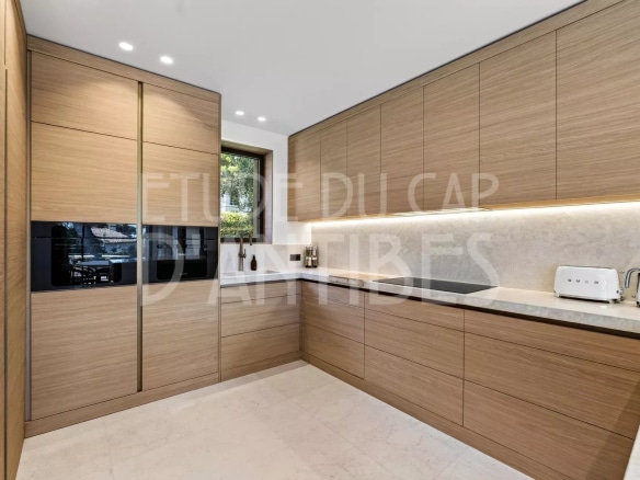 Cuisine moderne en bois avec plan de travail en marbre dans une villa à Antibes.