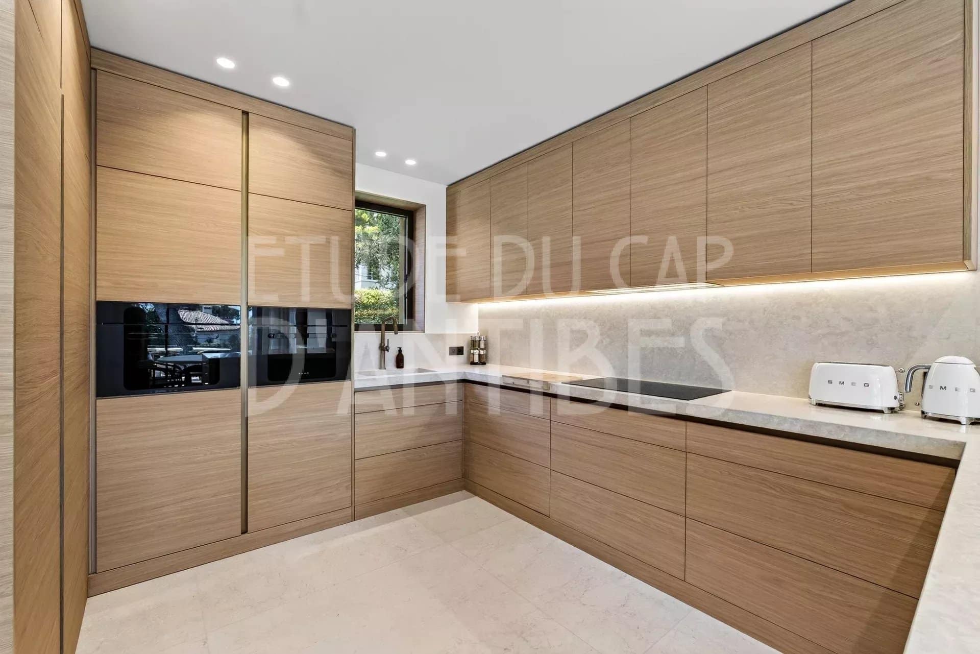 Cuisine moderne en bois avec plan de travail en marbre dans une villa à Antibes.