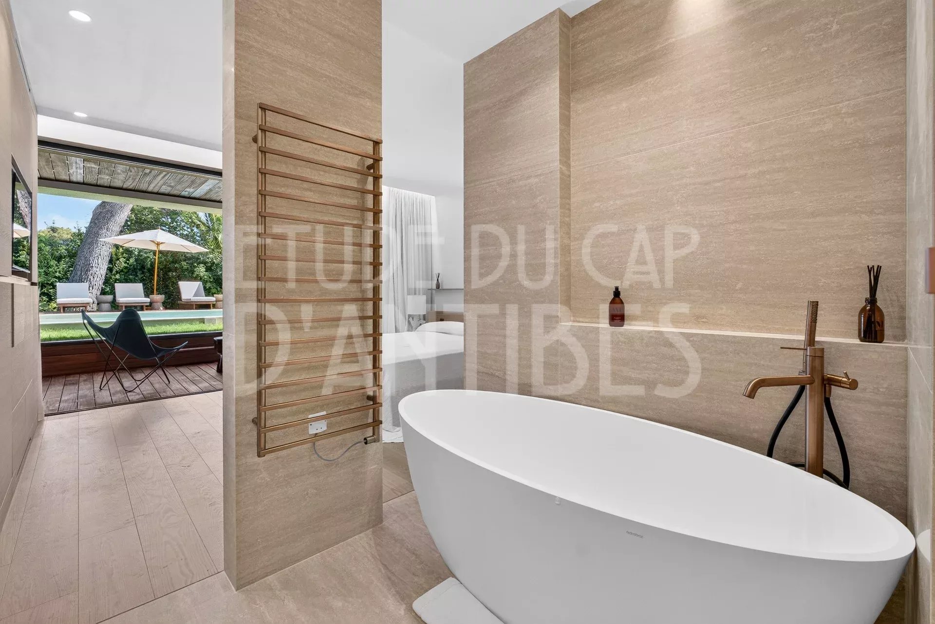 Salle de bain moderne avec baignoire, vue sur le jardin et la piscine.