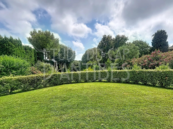 Jardin privatif d'un appartement dans une résidence avec piscine à Antibes, entouré de verdure.