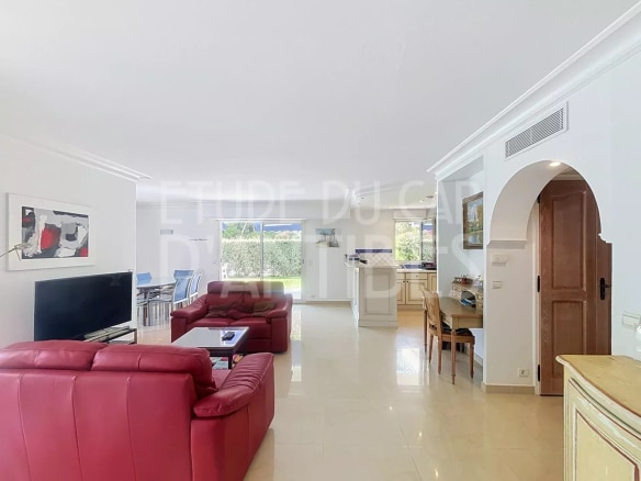 Intérieur d'un appartement de standing avec salon, cuisine ouverte et accès au jardin privatif.