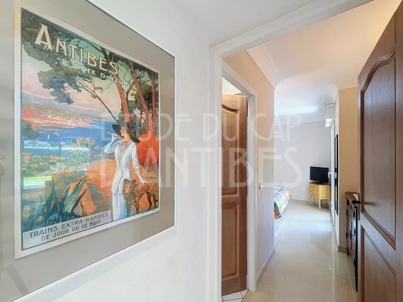 Intérieur d'un appartement à Antibes avec un couloir menant à un salon et une décoration murale.