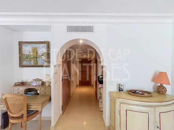 Intérieur d'un appartement de standing avec un bureau et un couloir lumineux.
