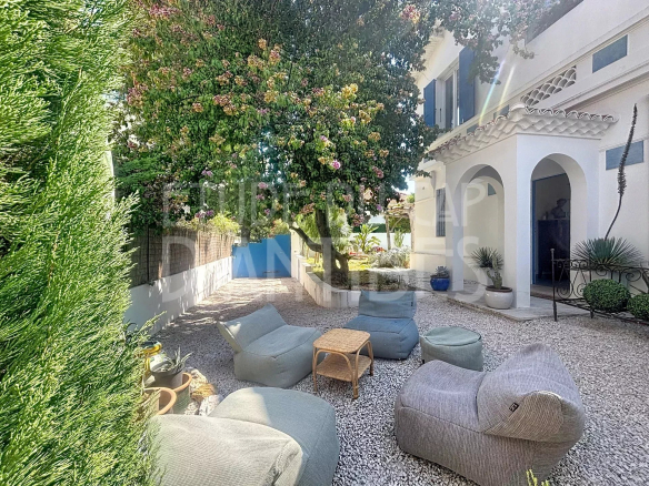 Jardin d'une villa méditerranéenne avec des fauteuils et un arbre fleuri, Antibes.