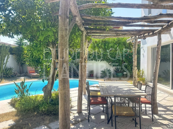 Terrasse en bois avec table et chaises près d'une piscine dans une villa méditerranéenne à Antibes.