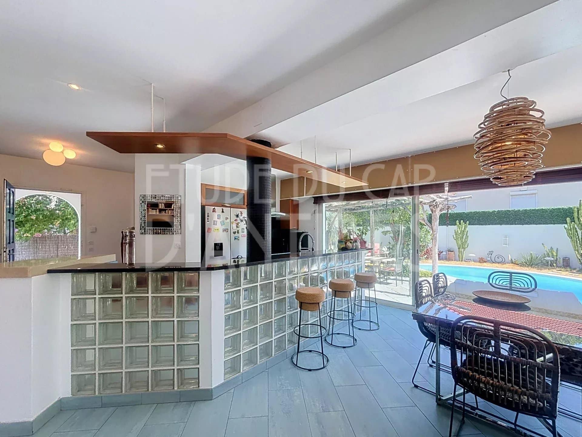 Intérieur d'une villa méditerranéenne avec cuisine ouverte et bar, vue sur la piscine.
