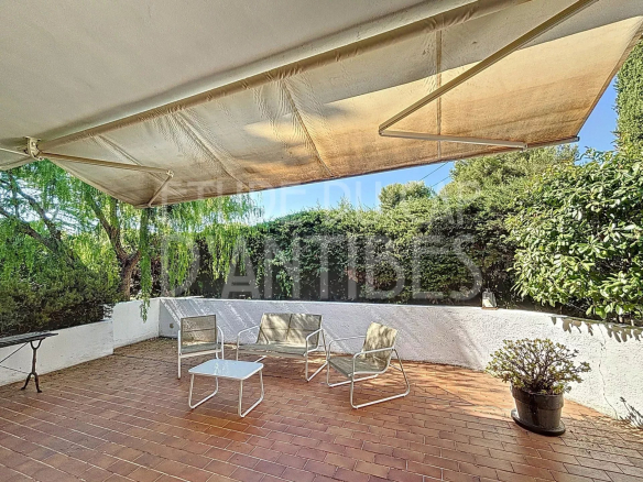 Shaded terrace of a Californian villa in Antibes with garden furniture.