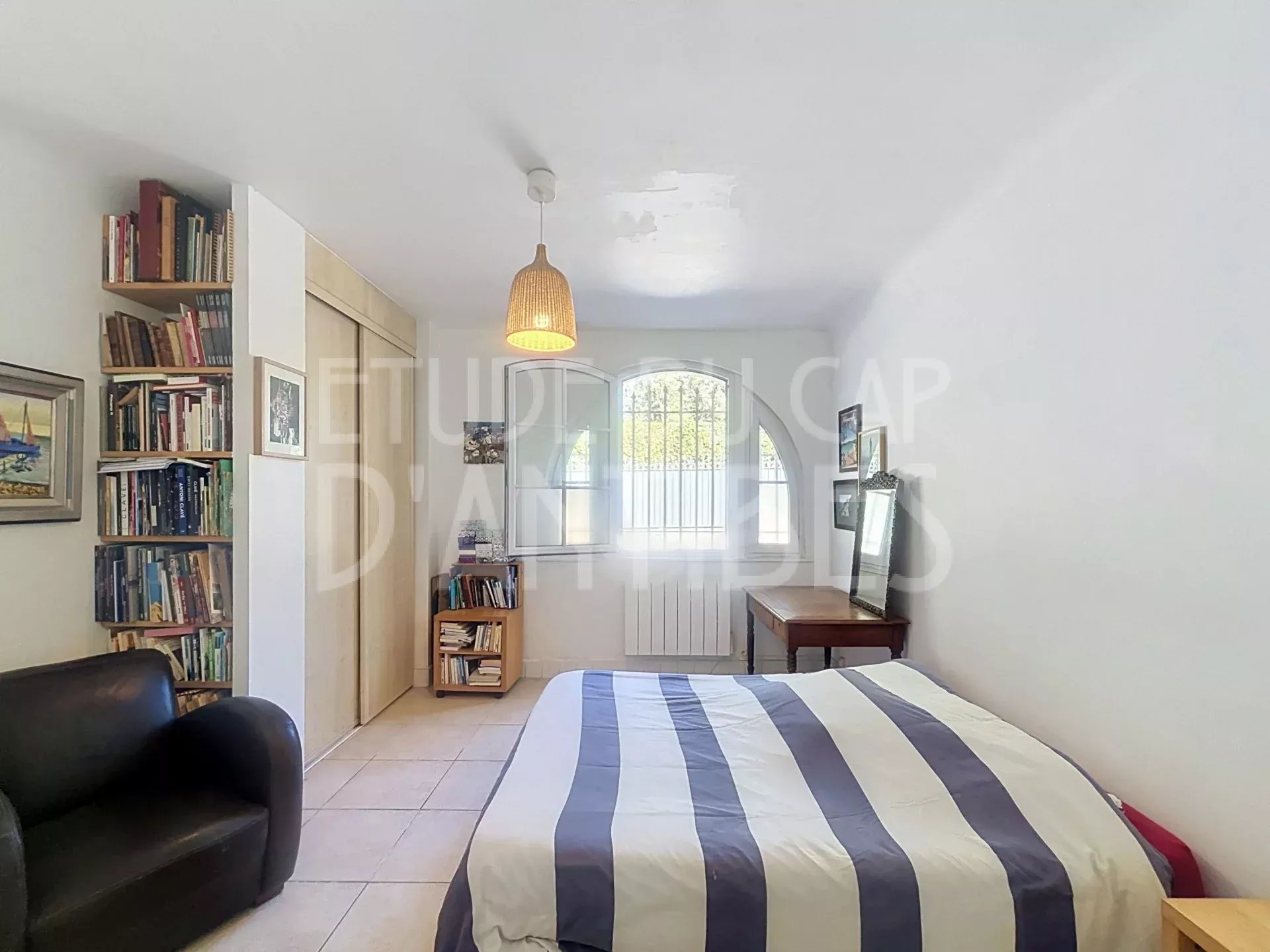 Chambre d’appartement duplex à Antibes Chambre d'un appartement duplex à Antibes avec lit, bibliothèque et meuble de rangement.