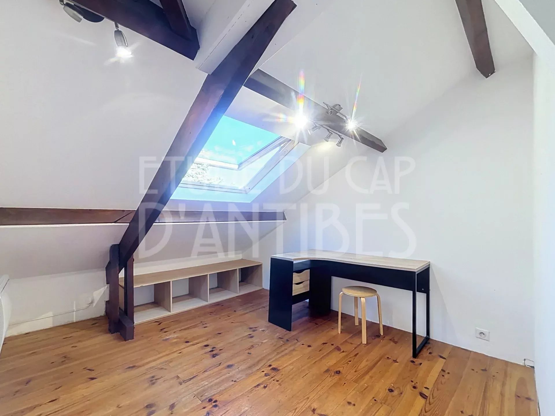 Intérieur d’un duplex à Antibes Intérieur d'un duplex avec poutres apparentes et bureau sous un vélux.