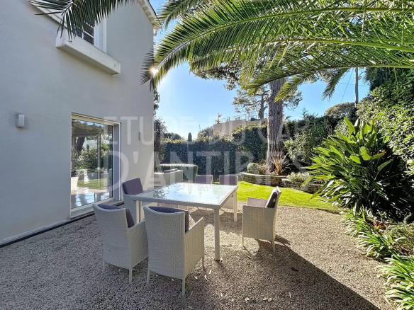 Terrace with table and chairs in the garden of a villa in Antibes, sunny and green.