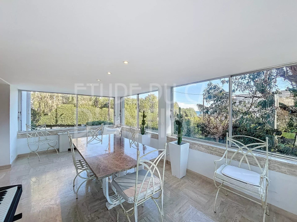 Bright dining room with large windows and garden views in a villa in Antibes.