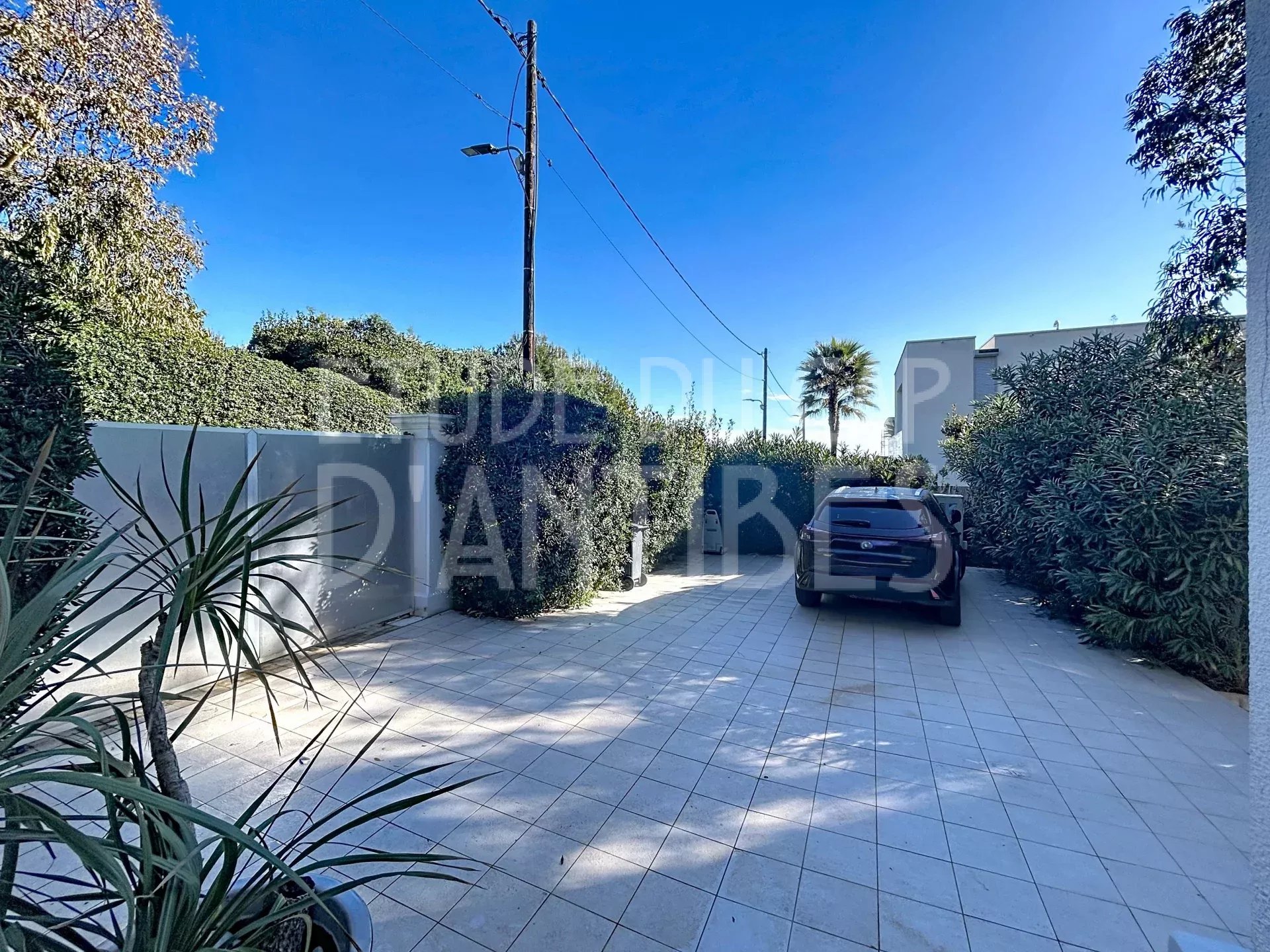 Driveway to the villa in Antibes Driveway to a villa with a parked car, surrounded by greenery in Antibes.