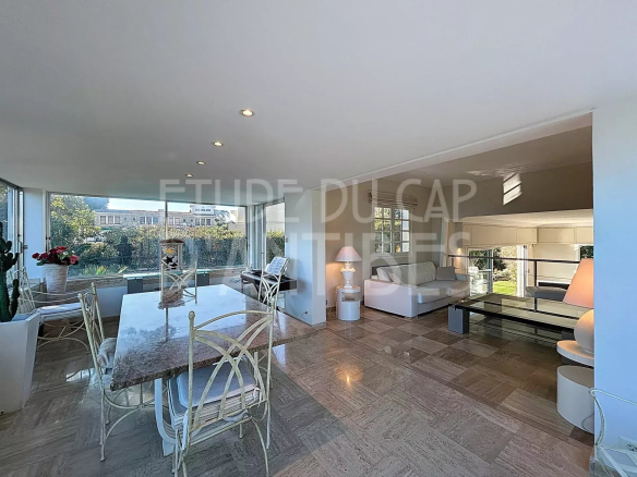 Interior of a modern villa with living room and dining room, bathed in natural light.