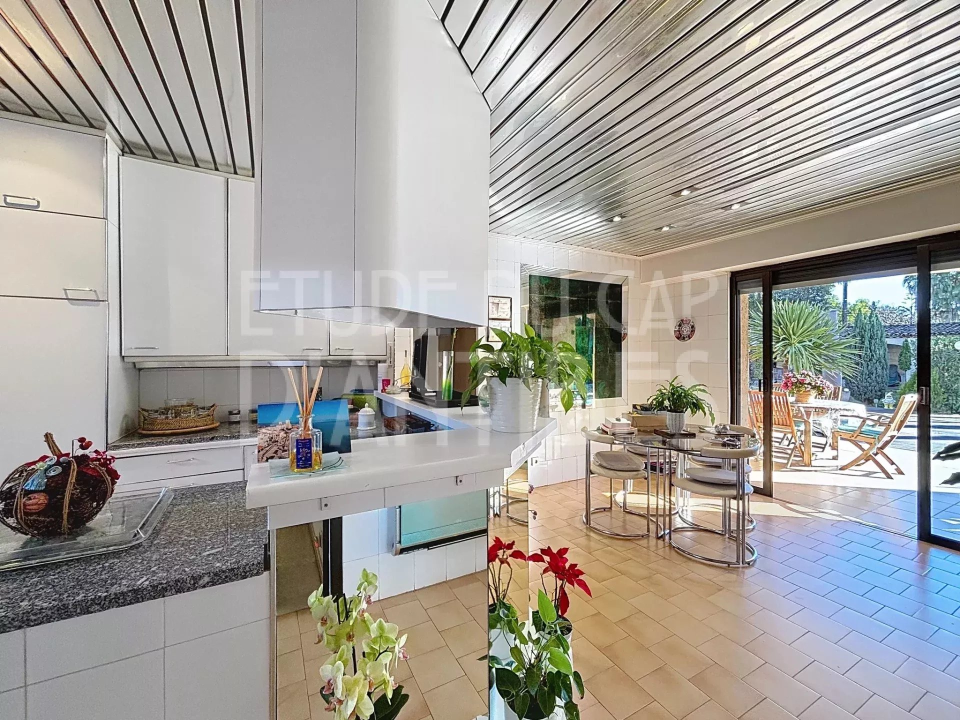 Intérieur d’une villa à Antibes Intérieur d'une villa lumineuse avec cuisine ouverte et salle à manger, vue sur la terrasse et la piscine.