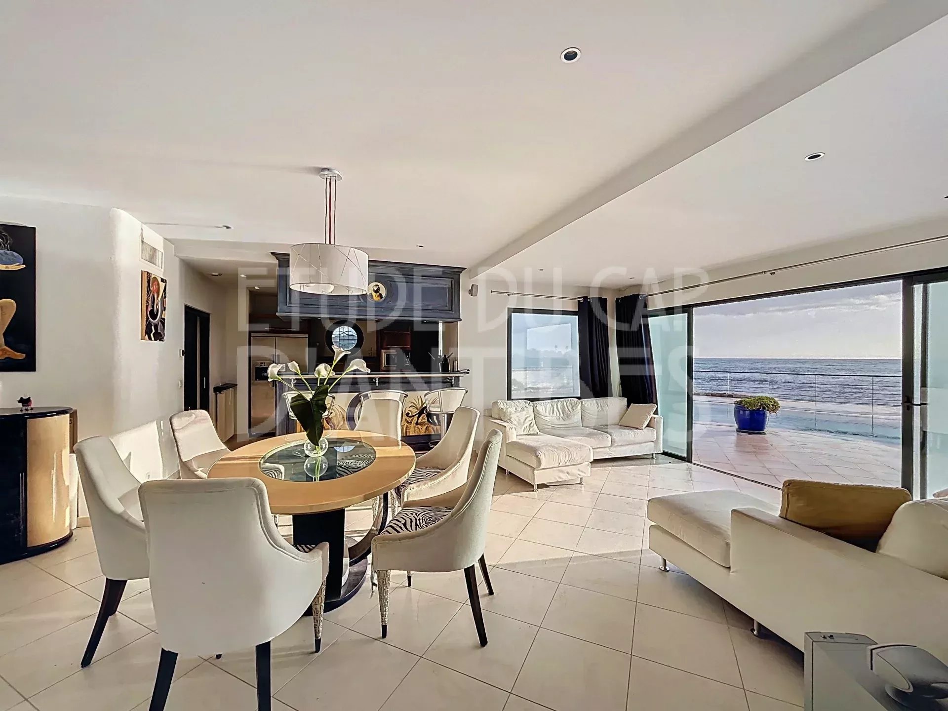 Intérieur de la villa ‘Pieds dans l’eau’ Intérieur d'une villa moderne avec vue sur la mer, salon lumineux et salle à manger.