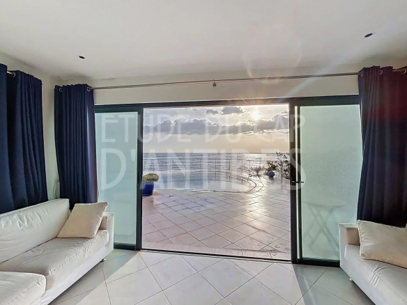 Intérieur d'une villa avec vue sur la mer, grandes baies vitrées et salon lumineux.