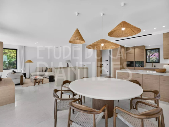 Intérieur d'une villa moderne avec salle à manger, cuisine ouverte et salon lumineux.