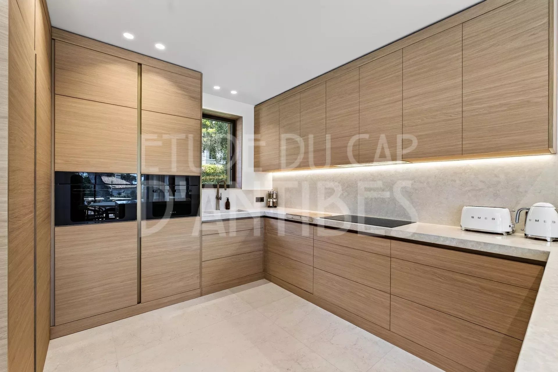 Cuisine de villa à Antibes Cuisine moderne en bois avec plans de travail en marbre dans une villa à Antibes.