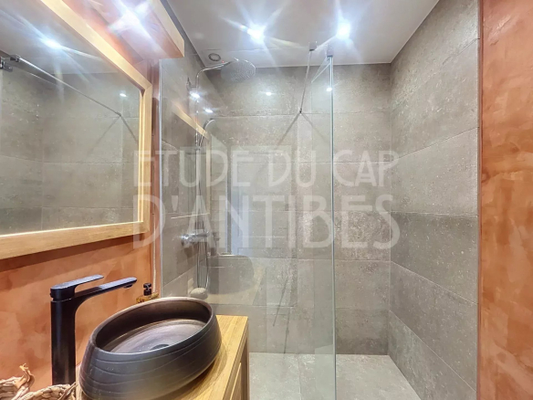Salle de bain moderne avec douche en verre et lavabo en bois dans une villa à Antibes.