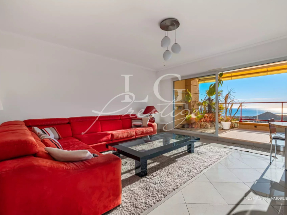 Bright living room with a red sectional sofa, glass coffee table, and balcony doors to an ocean view.