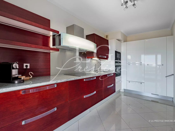 Modern kitchen with glossy white tall cabinets, dark red wood lower cabinets, and stainless steel appliances along a granite countertop.