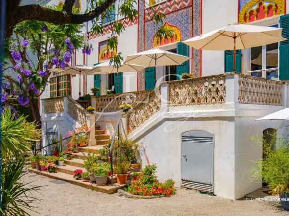 Entrance to a historic property with stairs and parasols, Cannes