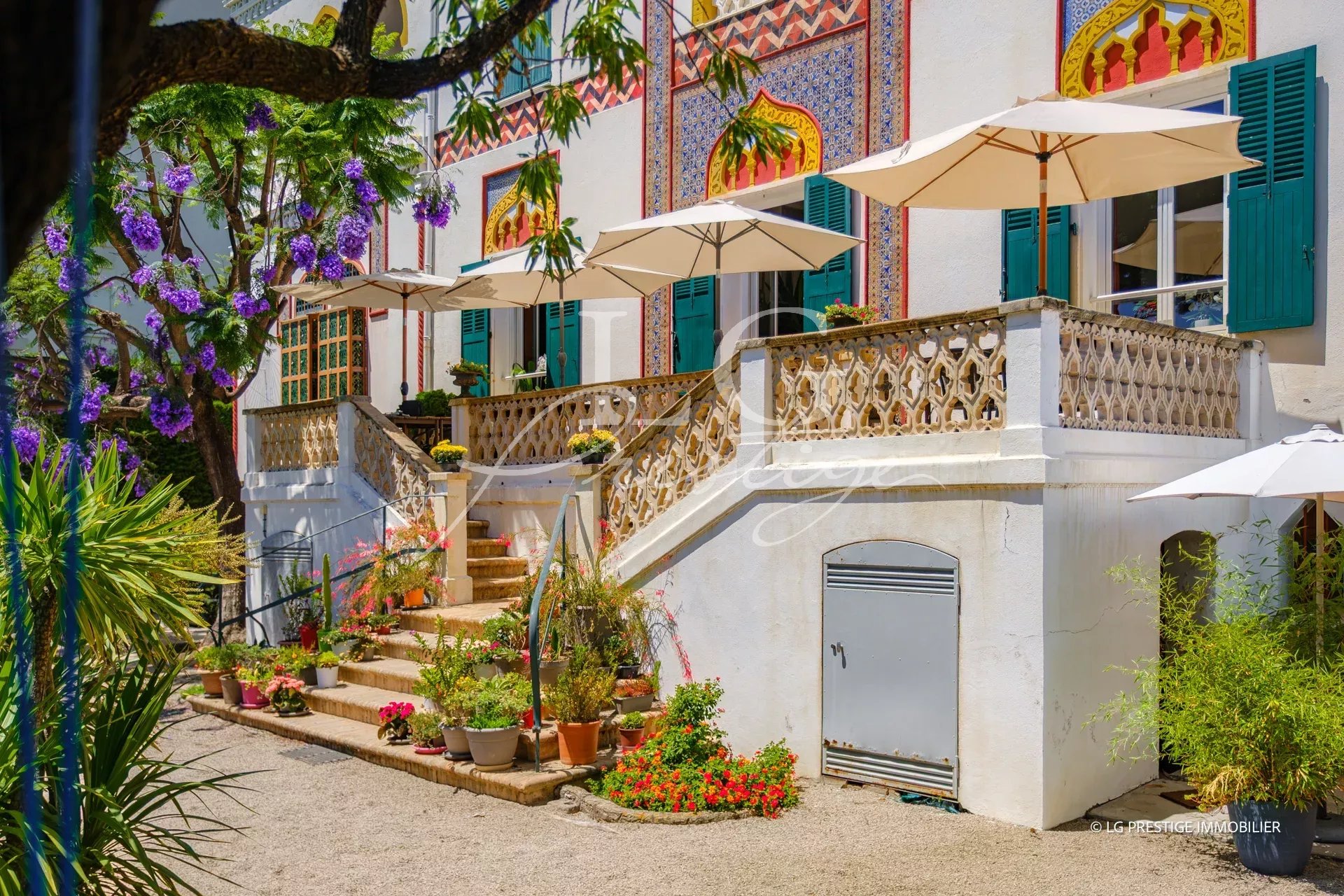 Entrance to a historic property with stairs and parasols, Cannes