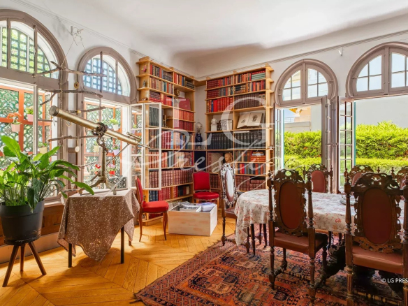 Interior of an elegant dining room with arched windows and bookshelves filled with books.