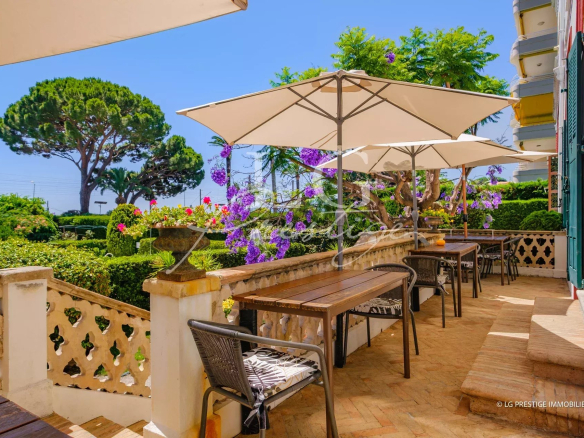 Terrace with wooden tables and parasols, surrounded by greenery and flowers in Cannes.