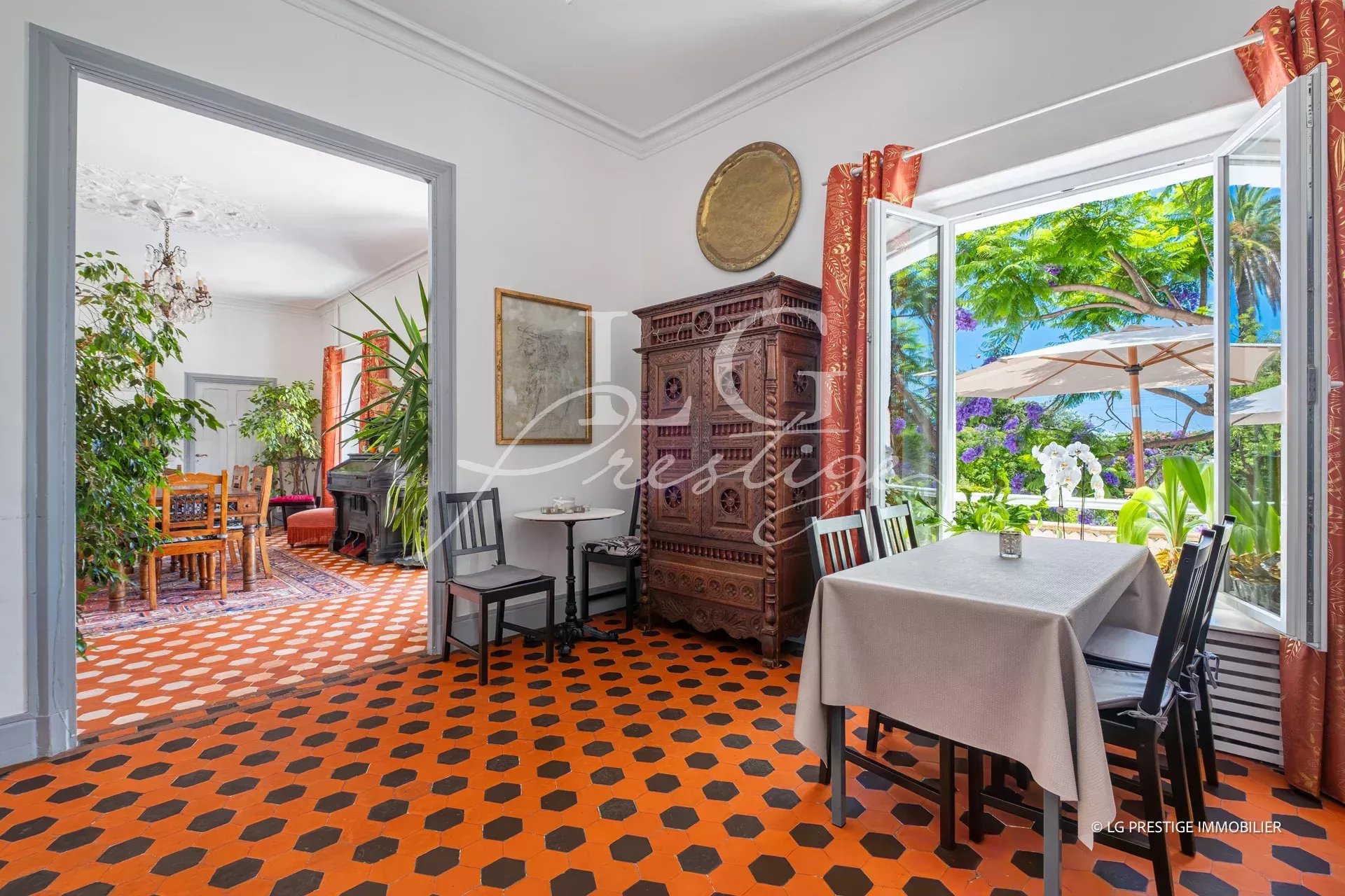 Interior of a property with orange tiles and antique furniture, overlooking the garden.