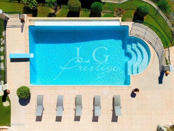 Aerial view of a swimming pool surrounded by sun loungers in a villa.