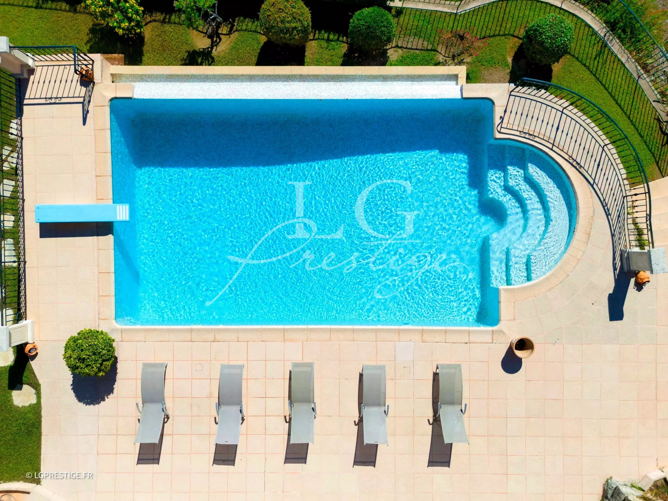 Aerial view of a swimming pool surrounded by sun loungers in a villa.
