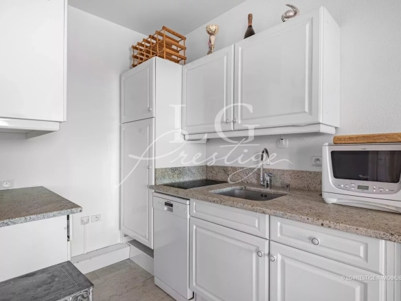 Modern kitchen with white cabinets and granite worktop.