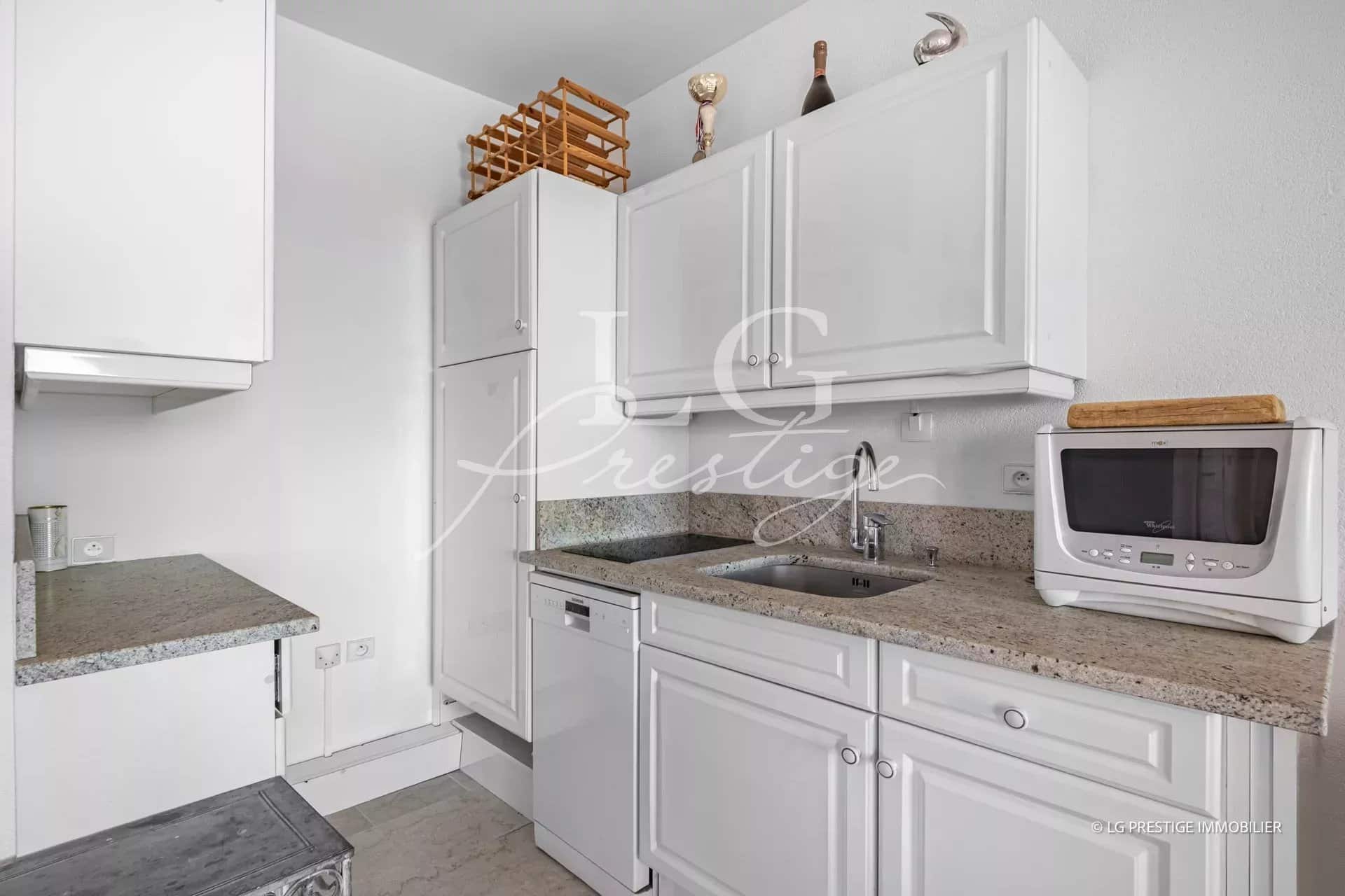 Modern kitchen with white cabinets and granite worktop.