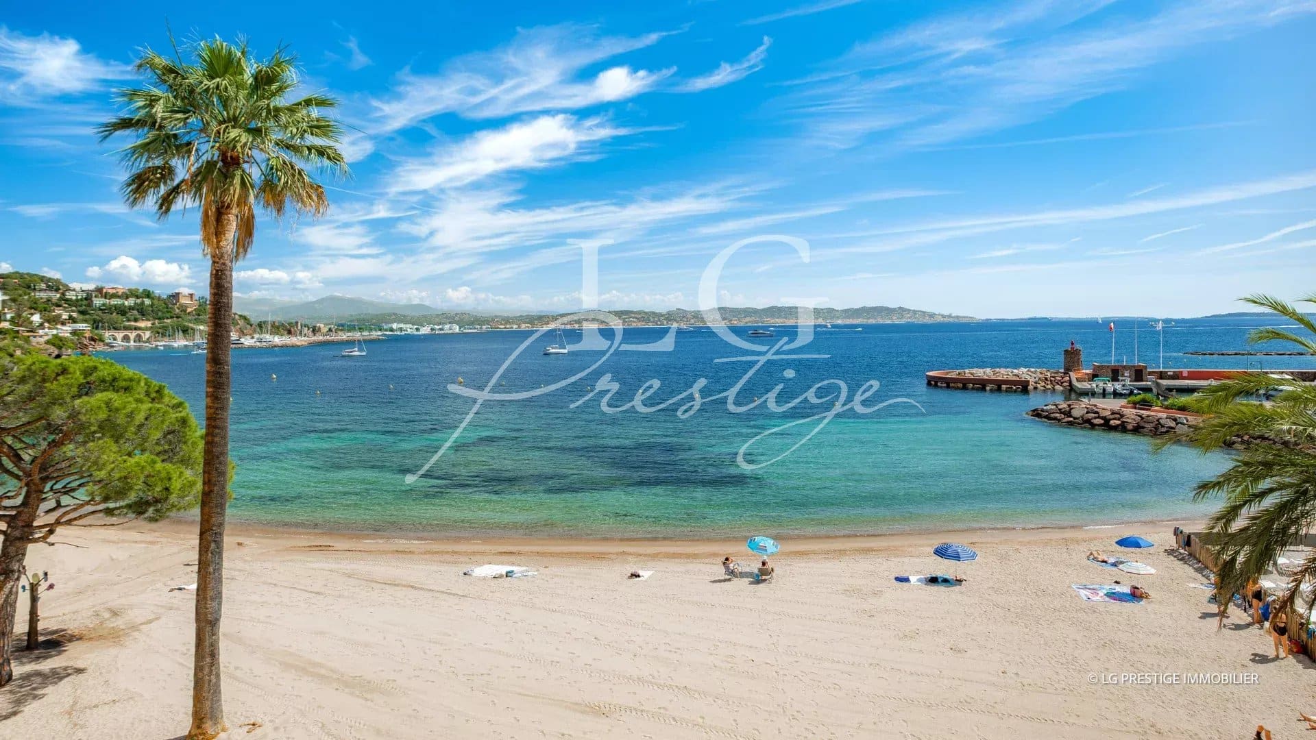 Beach at Théoule-sur-Mer with a view of the sea and palm trees in the foreground.