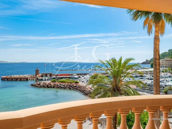 Panoramic sea view from an apartment terrace in Théoule-sur-Mer, with palm trees and port in the background.