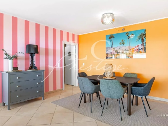 Interior of an apartment with a round table and chairs, walls decorated in pink and orange.