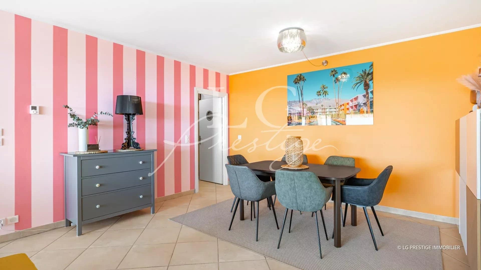Interior of an apartment with a round table and chairs, walls decorated in pink and orange.