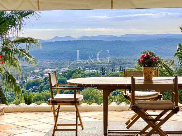 Terrasse avec vue panoramique sur la vallée et les montagnes, mobilier de jardin en bois.