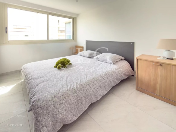 Room in a modern apartment with a double bed and a window letting in light.