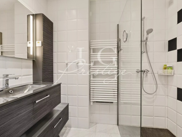Modern bathroom with shower and sink, black and white tiles.