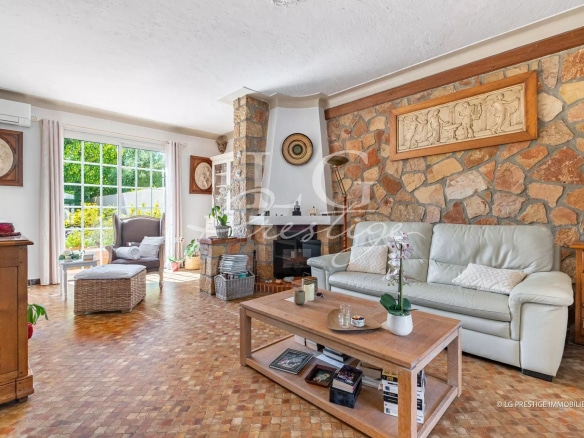 Intérieur d'une maison de plain-pied à Mougins avec salon lumineux et cheminée en pierre.