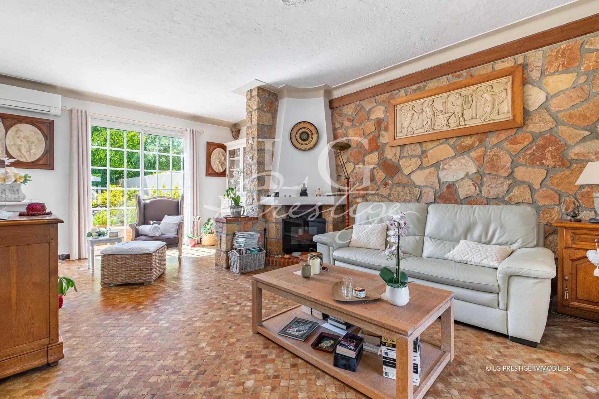 Intérieur d'une maison de plain-pied à Mougins avec salon lumineux et cheminée en pierre.