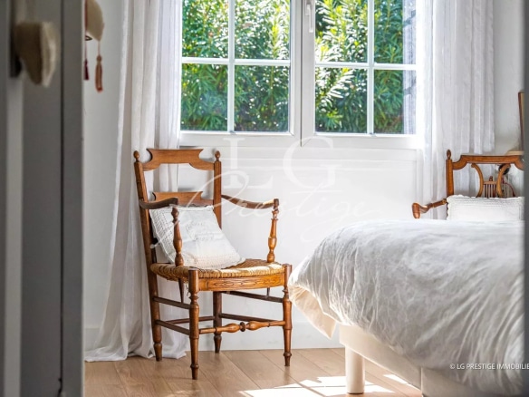 Chambre lumineuse avec chaises en bois et fenêtre donnant sur un jardin