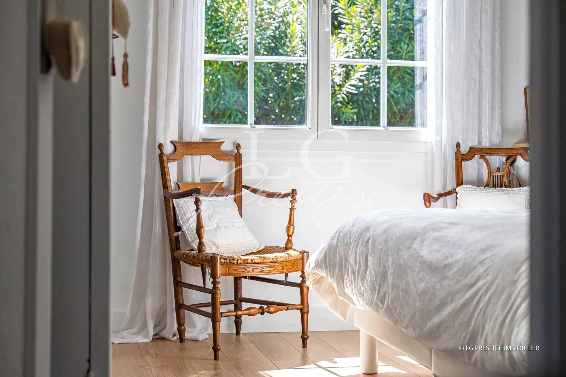 Chambre lumineuse avec chaises en bois et fenêtre donnant sur un jardin