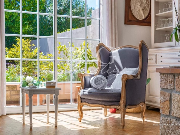 Intérieur d'une maison avec un fauteuil et une vue sur un jardin à Mougins.