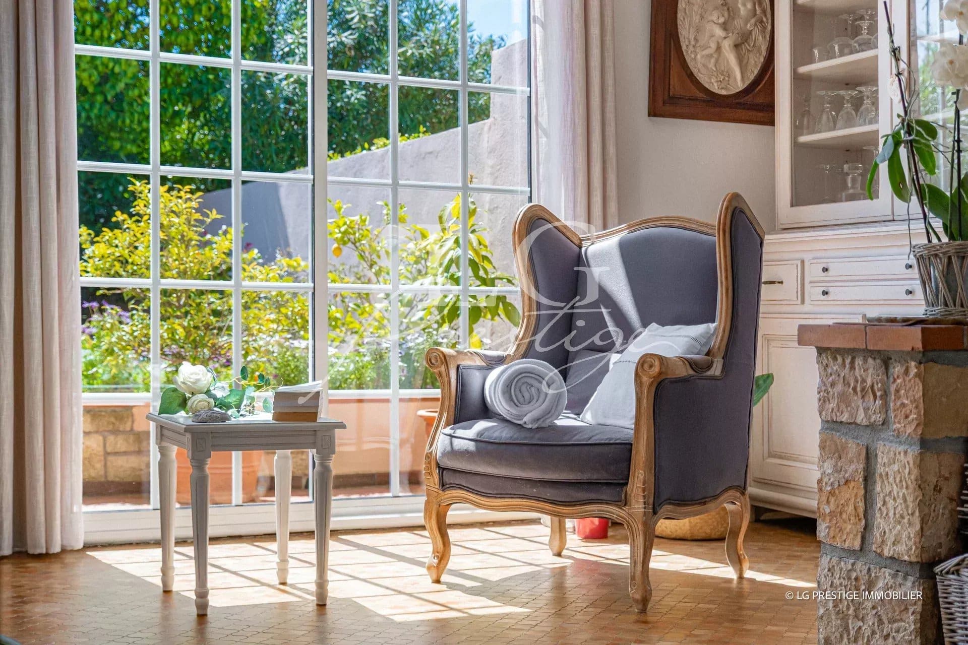 Intérieur d'une maison avec un fauteuil et une vue sur un jardin à Mougins.