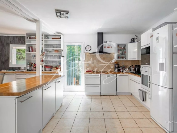 Cuisine moderne et lumineuse d'une villa de plain-pied à Fayence, avec meubles blancs et plan de travail en bois.